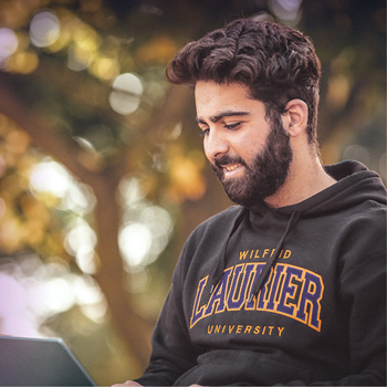 student smiling on his laptop outside