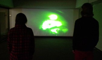 Dark gallery interior. Cast on the wall is green abstract image