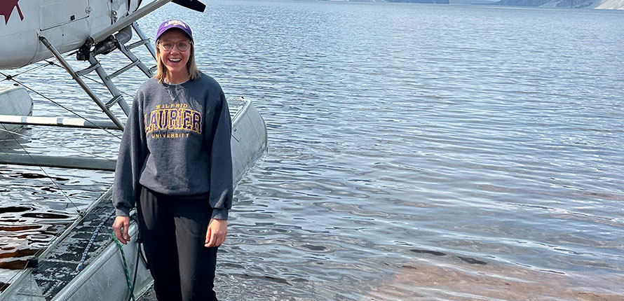 Kate Cain standing in a northern lake beside a float plane