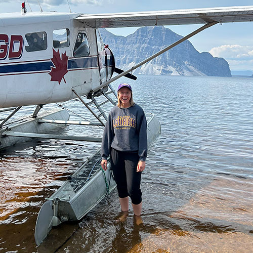 Kate Cain standing in a lake beside a float plane