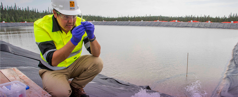 Scientist testing water beside a large reservoir
