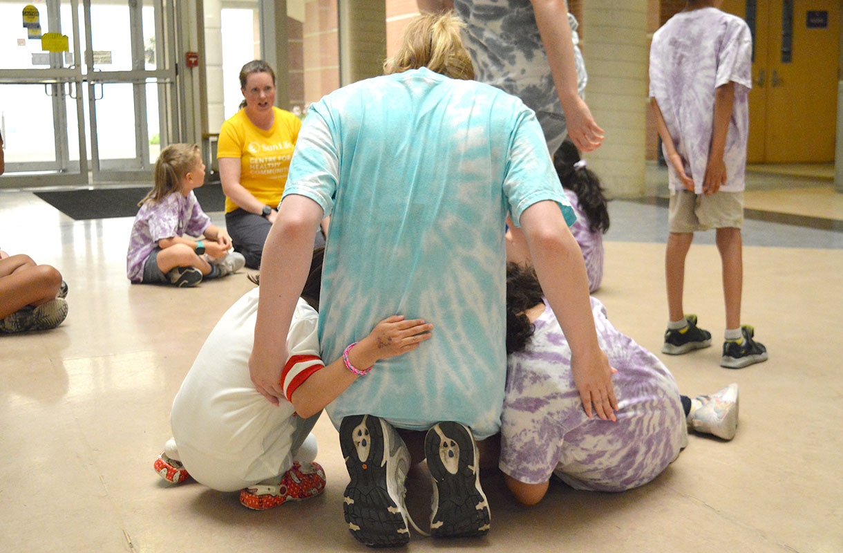 Counsellor's back and children hugging from behind
