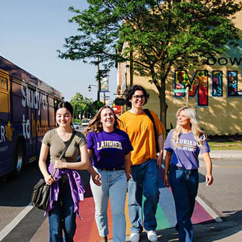 group of students next to a Laurier branded bus walking downtown Milton