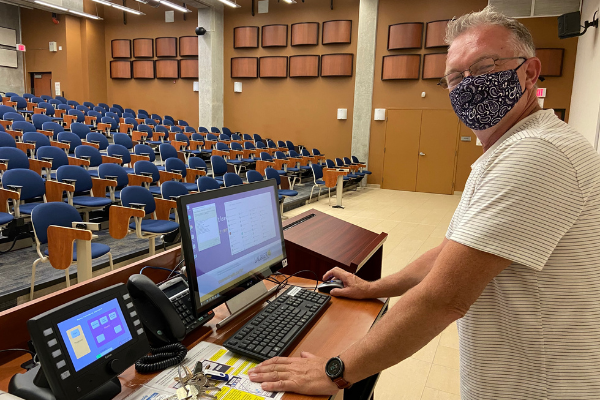 man standing at a workstation wearing a mask