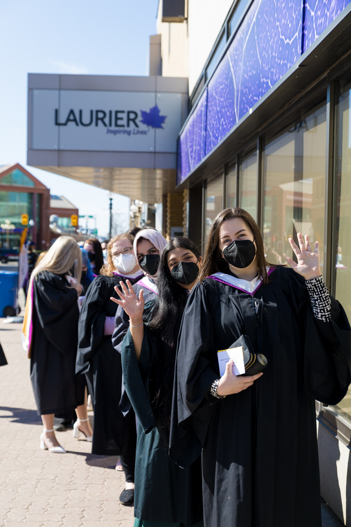 Masked graduates waving during ceremony