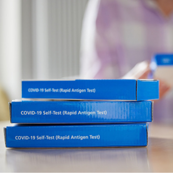 Three boxes of rapid antigen tests stacked on each other.