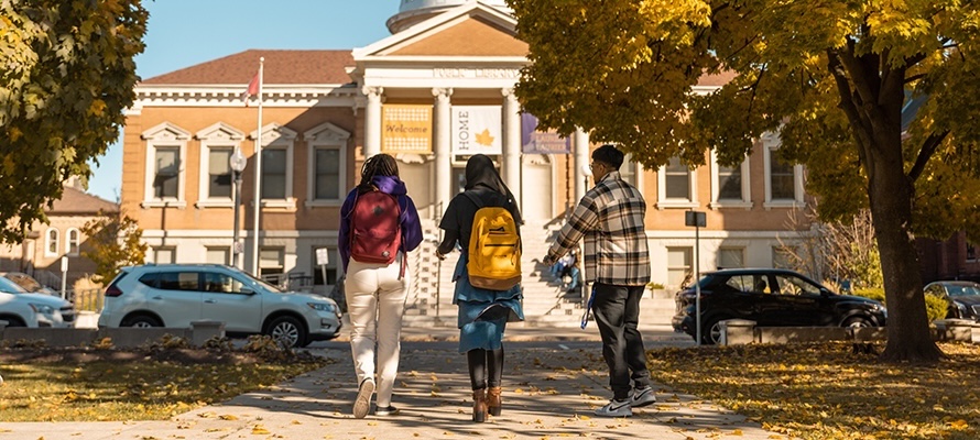 Three students walk in front of Carnegie Building