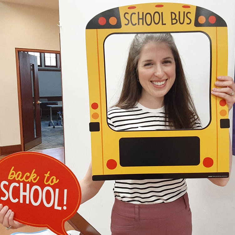 A young woman poses with a school bus prop frame