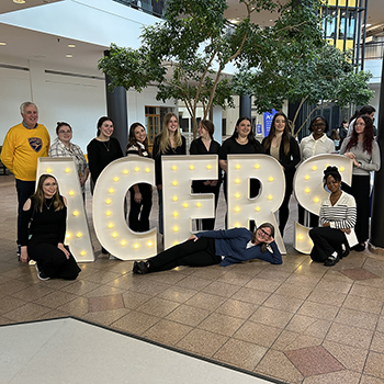Student researchers pose with illuminated letters reading ACERS